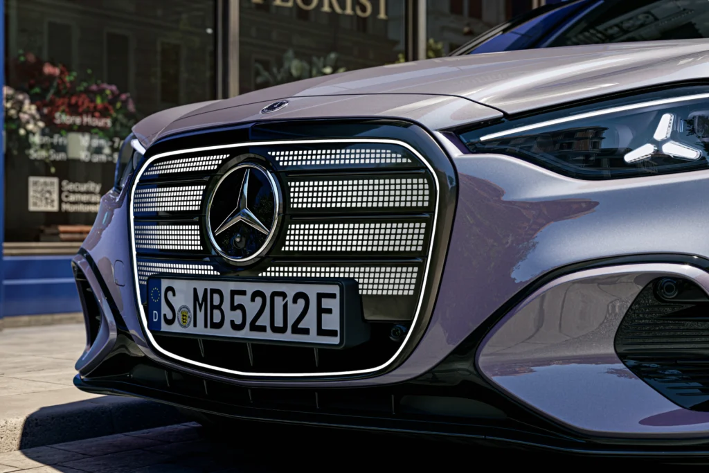 Front view of a silver Mercedes-Benz with illuminated grille and emblem, license plate visible (€EU).